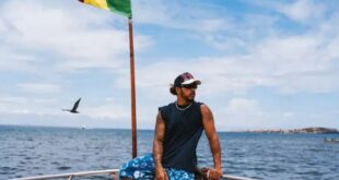 Emu par sa visite à la maison des esclaves sur l'île de Gorée, Lewis Hamilton pose dos à la mer et au drapeau du Sénégal